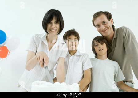 Famille avec gâteau d'anniversaire, woman holding knife, tous smiling Banque D'Images