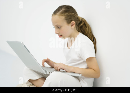 Petite fille à l'aide d'un ordinateur portable, side view Banque D'Images