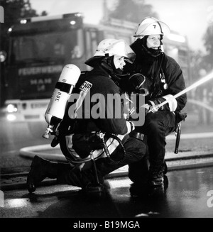 Les jeunes pompiers avec une protection respiratoire et extincteur en action, de nuit, noir et blanc, Allemagne Banque D'Images
