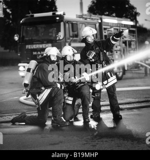 Les jeunes pompiers avec une protection respiratoire et extincteur en action, de nuit, noir et blanc, Allemagne Banque D'Images