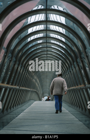 Un homme marche seul à travers le tunnel d'une passerelle couverte dans La Defense Paris France Banque D'Images