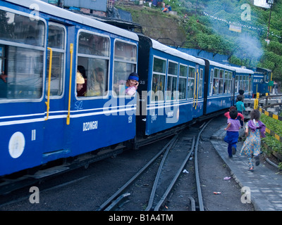 Les enfants courir après le petit train qu'il quitte la gare de Darjeeling Banque D'Images