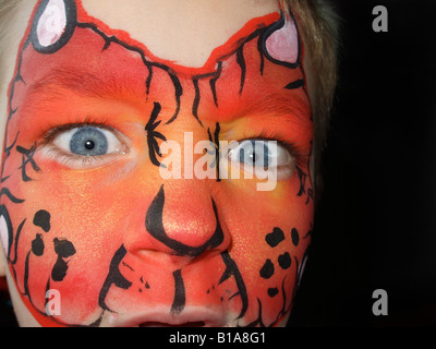 Boy (6-8) avec Dragon Rouge, le visage peint et des yeux bleus à directement à l'appareil photo Banque D'Images