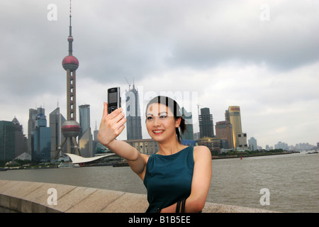 Young woman taking photo du soi avec le téléphone appareil photo,gratte-ciel en arrière-plan comme Pudong Shanghai,Chine, Banque D'Images