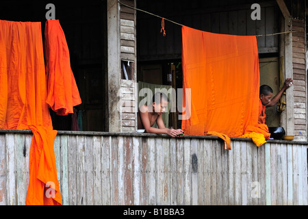 Un novice et un des moines de détente sur le couloir de leur maison en bois au temple Wat wang wiwekaram Sangkhla buri, Thaïlande en Banque D'Images