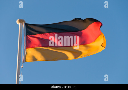 Un drapeau allemand dans le vent sur un fond de ciel bleu Banque D'Images
