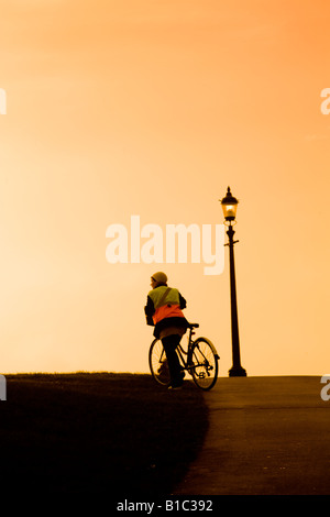 Femme pousse son vélo sur Primrose Hill London au coucher du soleil Banque D'Images