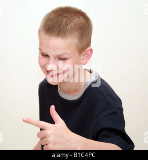 Garçon en studio de sourire et de faire une Drôle de tronche et en pointant sa main Banque D'Images