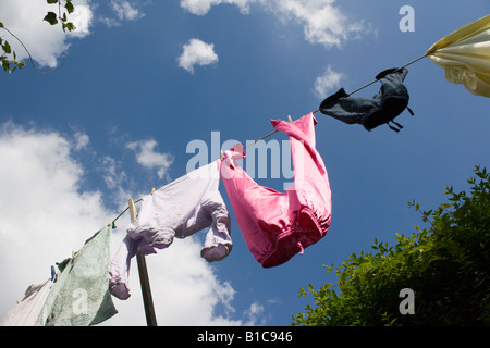 Vêtements accrochés sur une corde à linge avec une couverture et un fond de ciel bleu. Banque D'Images