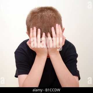 Garçon en studio avec les mains sur le visage de pleurer Banque D'Images
