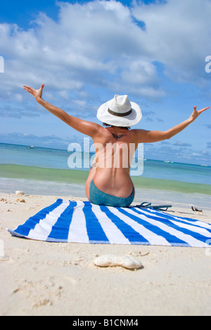Femme avec chapeau de soleil bénéficie de la plage de vacances, assis sur une serviette à rayures, Philippines Banque D'Images