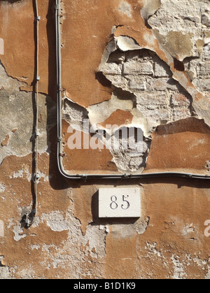 Décollement de peinture orange sur le vieux mur de la propriété en Italie Banque D'Images