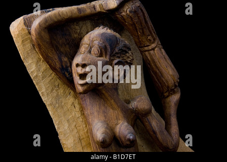 Vue rapprochée de la tête d'une femme africaine en bois sculpté portant un tas de broussailles Découper sur fond noir Banque D'Images