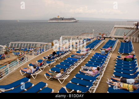 Cunard QE2 avec les passagers de vous détendre sur la terrasse avec P O envoi Arcadia à l'ancre à proximité Banque D'Images