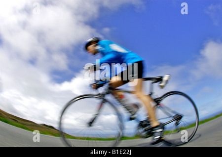 Une femme cycliste, équitation fast le long de la route côtière à Cornwall sur un vélo de course Banque D'Images