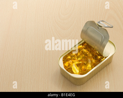 Des capsules d'huile de poisson dans un anneau fer-blanc sur la surface en bois Banque D'Images