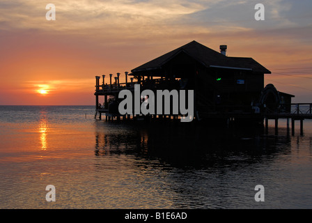 Coucher du soleil avec une maison en bois sur la rive à West End, West Bay, sur l'île de Roatan, Honduras, Amérique Centrale Banque D'Images