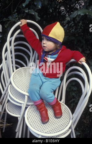 Tout-petit se trouve sur certaines chaises empilées dans l'arrière-cour à Brooklyn NY Banque D'Images
