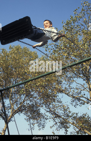 Garçon sur une balançoire à l'aire de jeux dans Brooklyn, NY Banque D'Images