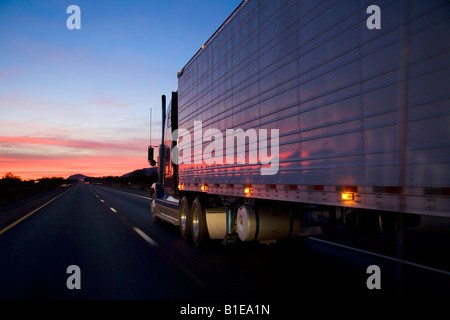 Semi-truck driving sur l'interstate I-10 en @ coucher de soleil près de Quartize hiver Arizona USA Banque D'Images