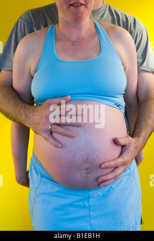 Vue sur le ventre de femme enceinte comme mari se tient derrière elle avec ses mains liées sur son estomac Alaska United States Banque D'Images