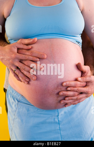 Vue sur le ventre de femme enceinte comme mari se tient derrière elle avec ses mains liées sur son estomac Alaska United States Banque D'Images