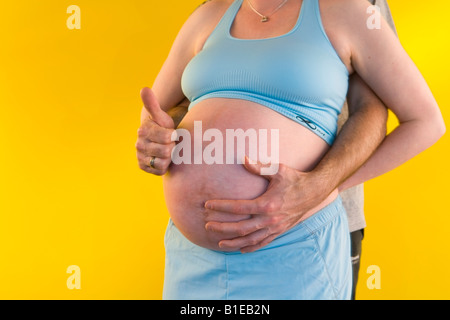 Vue sur le ventre de femme enceinte comme mari se tient derrière elle avec ses mains liées sur son estomac Alaska United States Banque D'Images