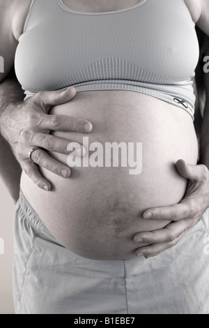 Vue sur le ventre de femme enceinte comme mari se tient derrière elle avec ses mains liées sur son estomac Alaska United States Banque D'Images