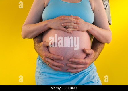 Vue sur le ventre de femme enceinte comme mari se tient derrière elle avec ses mains liées sur son estomac Alaska United States Banque D'Images