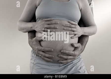 Vue sur le ventre de femme enceinte comme mari se tient derrière elle avec ses mains liées sur son estomac Alaska United States Banque D'Images