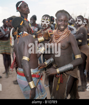Les jeunes hommes et les jeunes filles de la tribu Karo danse ensemble. Chaque homme porte un tabouret en bois, qui se double d'un oreiller la nuit. Banque D'Images
