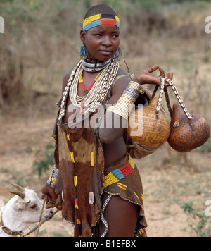 Une jolie femme Hamar dirige une chèvre à vendre à Dimeka, le plus grand marché de l'Hamar pays de sud-ouest de l'Éthiopie. Banque D'Images