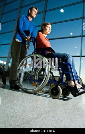 Portrait of a Mid adult man poussant une jeune femme assise dans un fauteuil roulant Banque D'Images