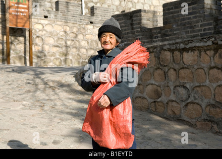 Une vieille femme chinoise pose pour quelques pièces près de la Grande Muraille de Chine Banque D'Images