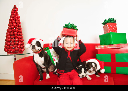 Asian boy avec des chiens et des cadeaux de Noël sur canapé Banque D'Images