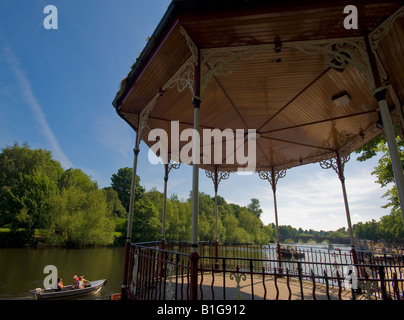 Les vacanciers dans un petit bateau à moteur passer un kiosque traditionnel sur les rives de la rivière Dee à Chester UK Banque D'Images