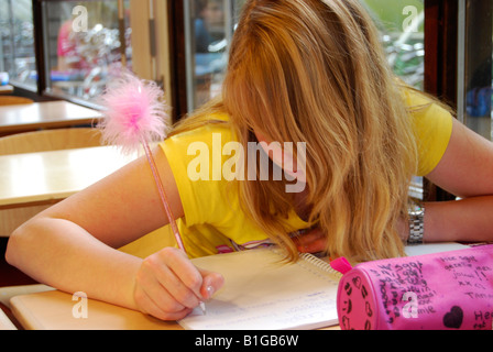 Student in class écrit dans son bloc-notes avec stylo moelleux Banque D'Images