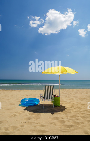 Un parasol jaune et du matériel de plage sur une plage de sable au bord de la mer en été. La Mata, Torrevieja, Espagne. Banque D'Images