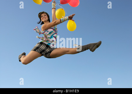 Jeune femme faisant des scissions au sein de la holding balloons Banque D'Images