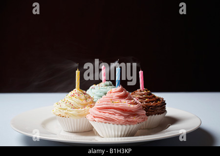 Cupcakes colorés avec des bougies d'anniversaire insuffle sur la plaque Banque D'Images