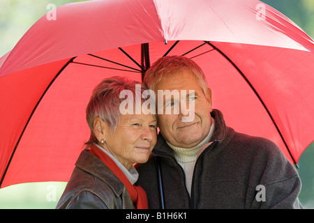 Couple à l'aide d'un parapluie rouge Banque D'Images