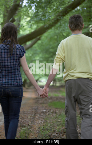 Couple walking through woods holding hands Banque D'Images