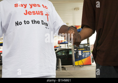 Détroit, Michigan activistes religieux inscrivez-vous les mains et priez à une station Sunoco pour la baisse du prix du gaz Banque D'Images