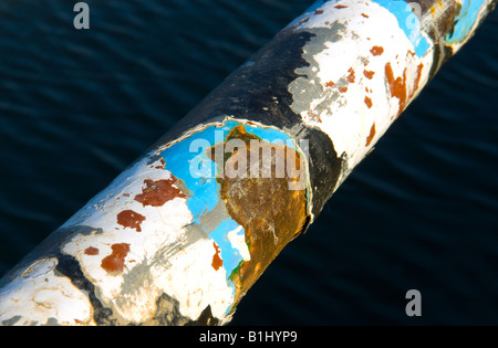 Un garde-corps de rouille sur pôle mer affichage de plusieurs couches de peinture enlevant Banque D'Images