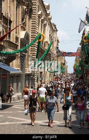 Les touristes et les gens de marcher sous le soleil le long de la rue de la République avec des décorations dans La Valette ou La Valette Malte Banque D'Images