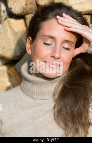 Jeune femme brownhaired portant un col roulé, bénéficiant d'une journée ensoleillée d'automne avec ferme les yeux Banque D'Images