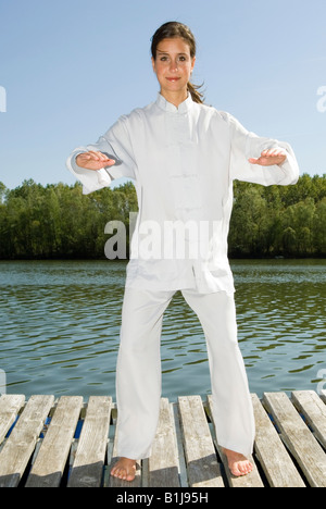 Young Pretty woman practicing Tai Chi sur une promenade au bord d'un lac, de base Banque D'Images