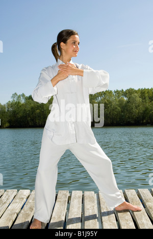 Young Pretty woman practicing Tai Chi sur une promenade sur un lac, saisissez la queue des oiseaux Banque D'Images