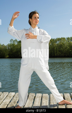 Young Pretty woman practicing Tai Chi sur une promenade sur un lac, saisissez la queue des oiseaux Banque D'Images