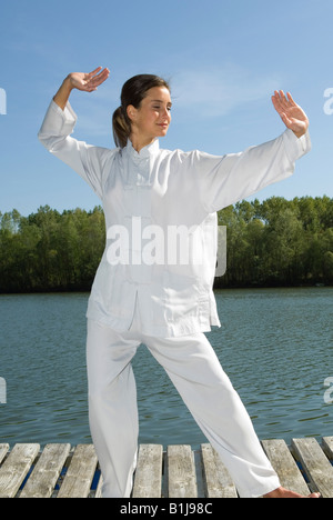 Young Pretty woman practicing Tai Chi sur une promenade sur un lac, saisissez la queue des oiseaux Banque D'Images